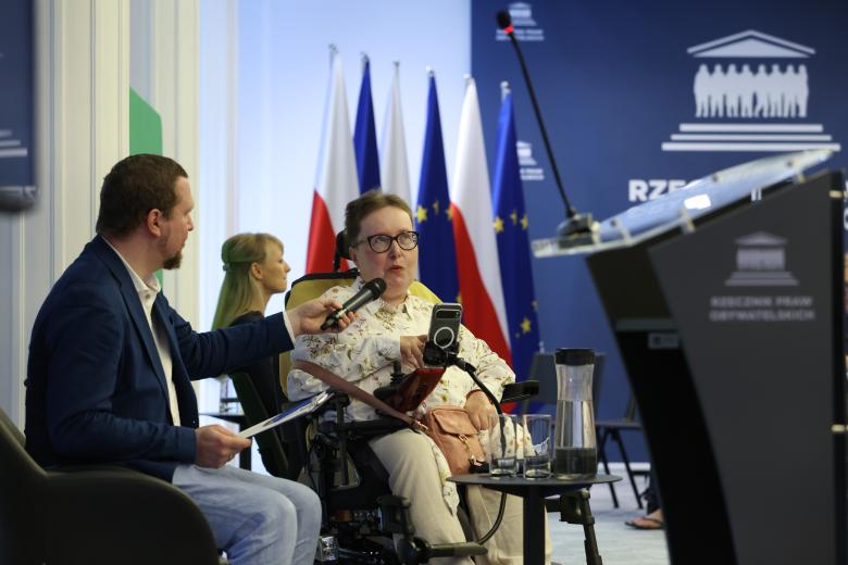 Patrycja Polczyk i Tomasz Przybysz-Przybyszewski rozmawiają siedząc przed uczestnikami wydarzenia. 