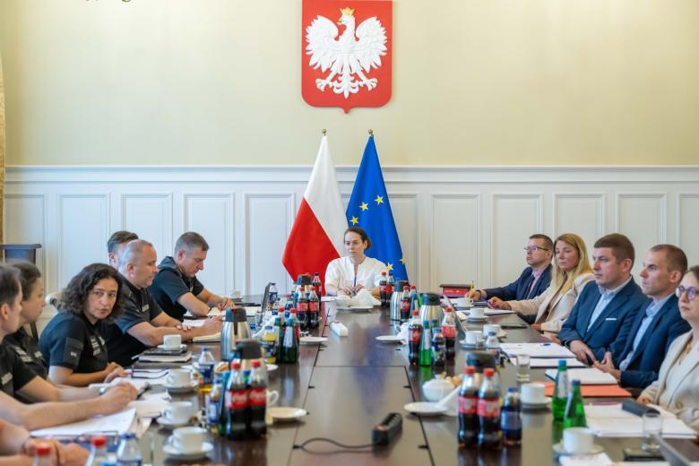 osoby siedzą za dużym stołem 