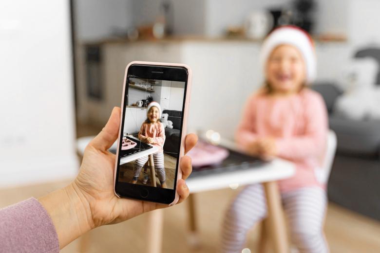 ręka trzyma smartfon którym robi zdjęcie małej dziewczynce 