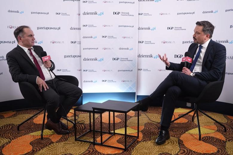 Zrzut ekranu z transmisji rozmowy. Dwie osoby rozmawiają siedząc na krzesłach w studiu i trzymając mikrofony