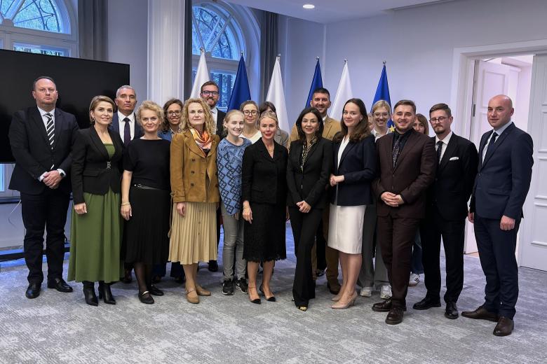 Kilkanaście osób pozuje na stojąco do wspólnego zdjęcia