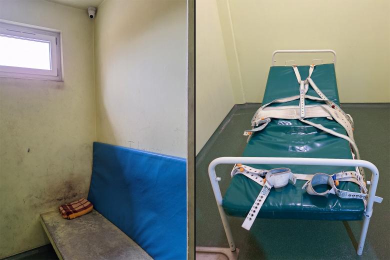 Dwa zdjęcia. Pierwsze zdjęcie przedstawia mały pokój z mocno zabrudzoną pryczą do spania z podniesionym cienkim, plastikowym materacem i kocem. Ściany w pomieszczeniu są bardzo brudne, znajduje się w nim niewielkie, wysoko położone okno i kamera. Poza tym w pomieszczeniu nie znajduje się żadne wyposażenie. Na drugim zdjęciu jest łóżko z pasami, którymi można unieruchomić leżącą na łóżku osobę.