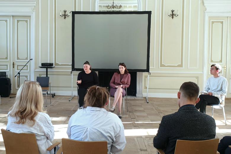 Kilkanaście osób siedzi na dużej auli konferencyjnej