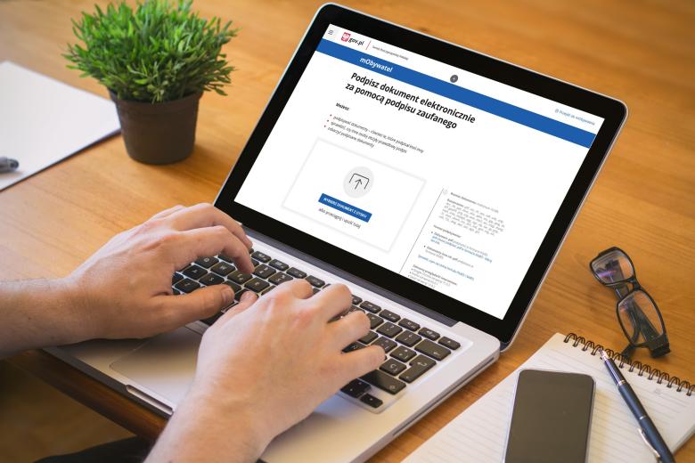 osoba pracująca na laptopie czyta rządową stronę internetową umożliwiająca podpisywanie dokumentów elektronicznie podpisem zaufanym