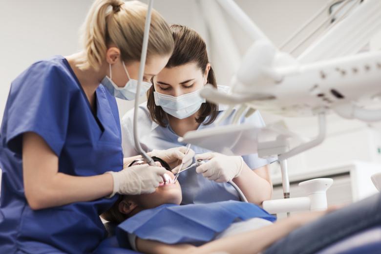 Dentystka i asystentka stomatologiczna podczas leczenia zębów pacjentowi 