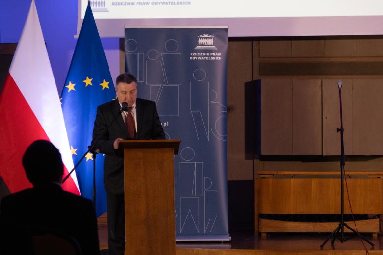 Piotr Gapiński wypowiada się stojąc przy mównicy