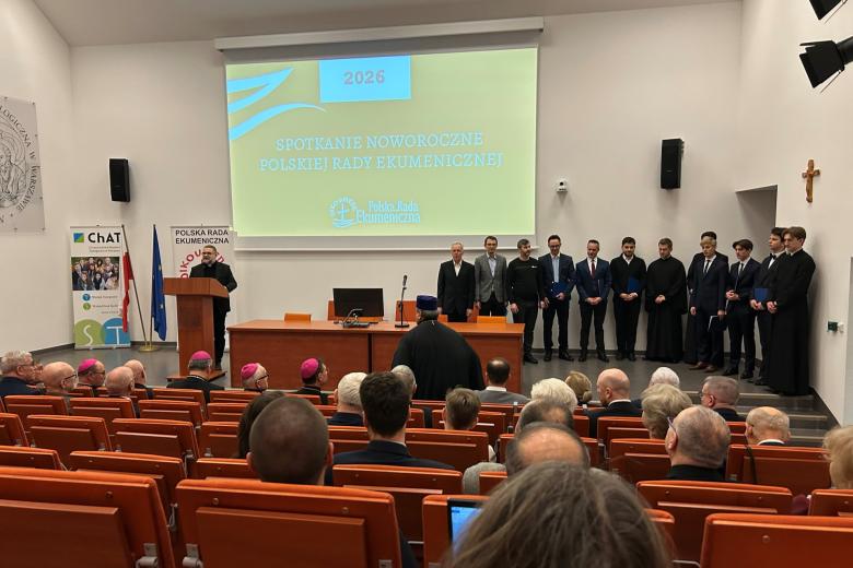 osoby siedzą w sali jedna przemawia