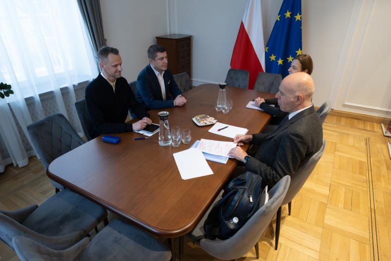 Cztery osoby siedzą przy stole i rozmawiają