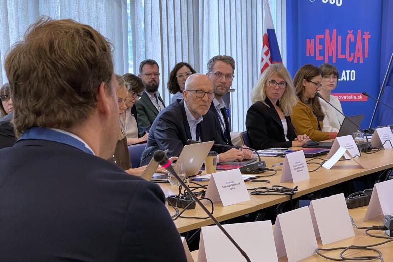 Kilka osób siedzi na fotelach przy stole