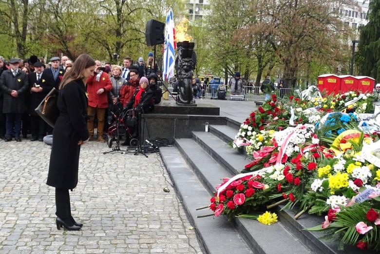 Kobieta skłania głowę przed pomnikiem 