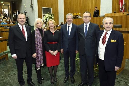 zdjęcie: od lewej stoi jeden mężczyzna, przy nim dwie kobiety, obok nich trzech mężczyzn, za nim jest mównica