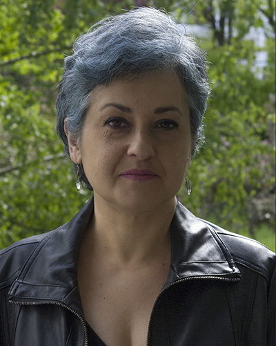 Kobieta w ciemnej kurtce na tle zieleni