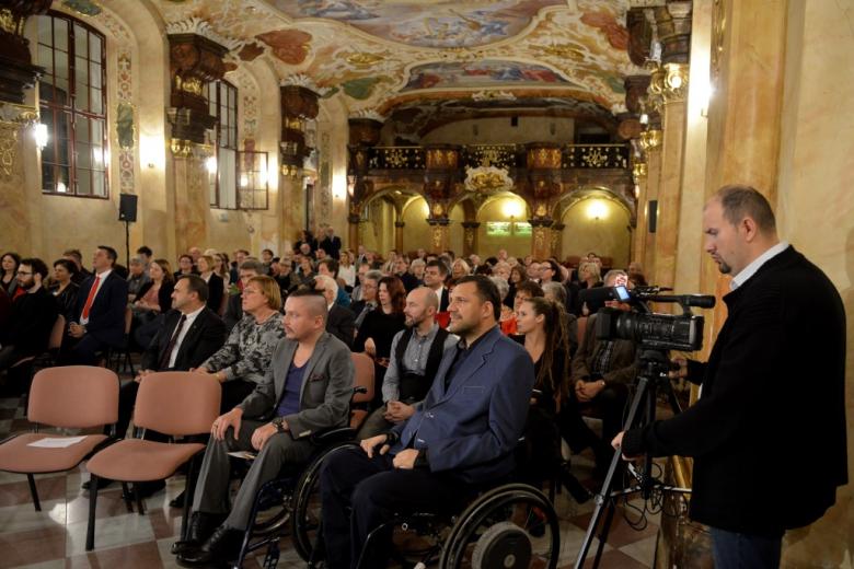 Ludzie w zabytkowej sali, dwaj mężczyźni na wózkach