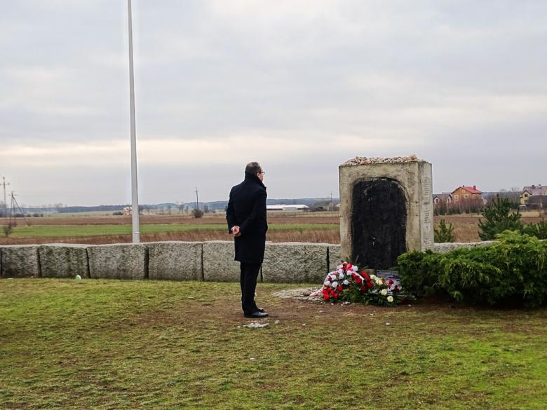 Mężczyzna przed pomnikiem, przed którym leżą kwiaty