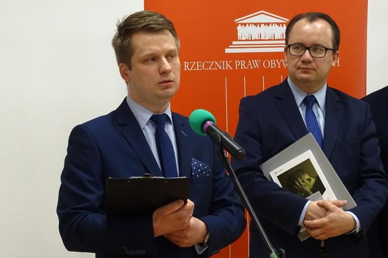 zdjęcie: dwaj mężczyźni w garniturach, jeden z nich trzyma książkę