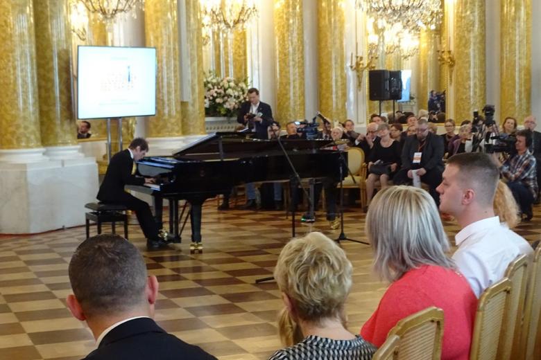 zdjęcie: przy fortepianie siedzi młody pianista