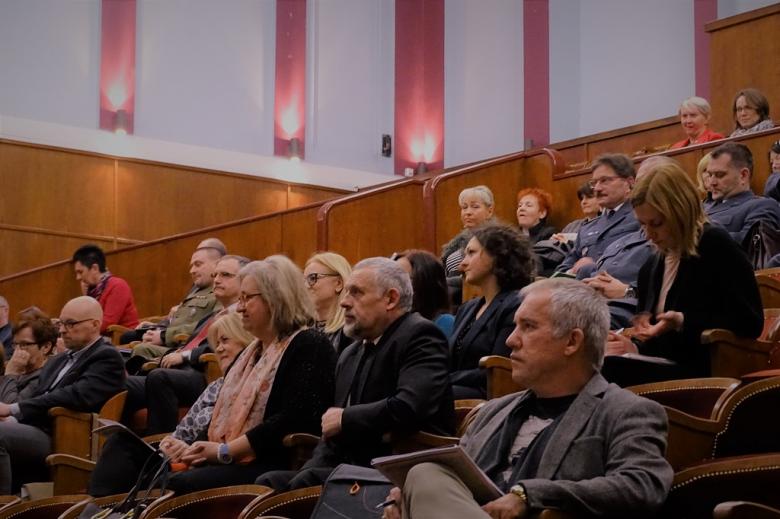 zdjęcie: na auli siedzi kilkadziesiąt osób, w tym osoby w mundurach