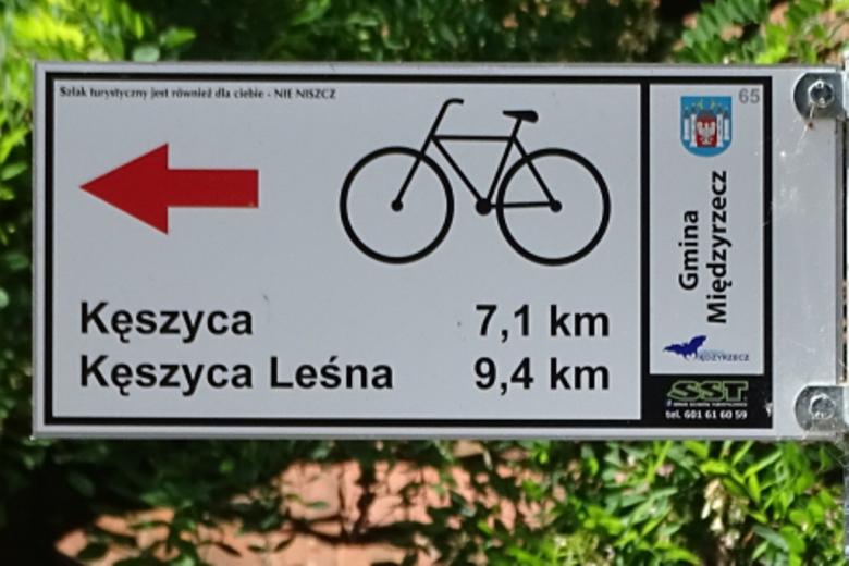 Zdjęcie: rower i strzałka na tabliczce informacyjnej o trasie rowerowej