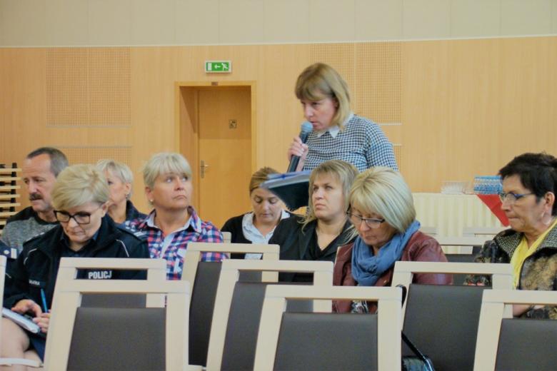 zdjęcie: pośród siedzących osób jedna z osób stoi