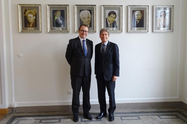 zdjęcie: dwóch mężczyzn w garniturach stoi na tle wiszących na wysokości ich głów portretów