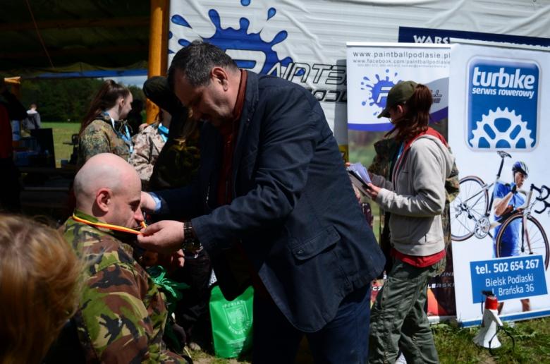 Zdjęcie: mężczyzna zawiesza medal na szyi zawodnika na wózku