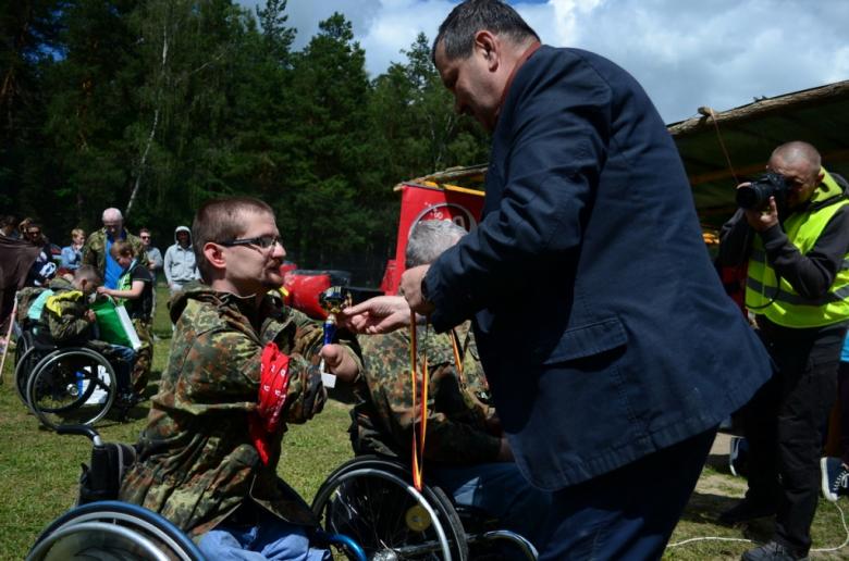 zdjęcie: mężczyzna wręcza mężczyźnie na wózku inwalidzkim złoty puchar