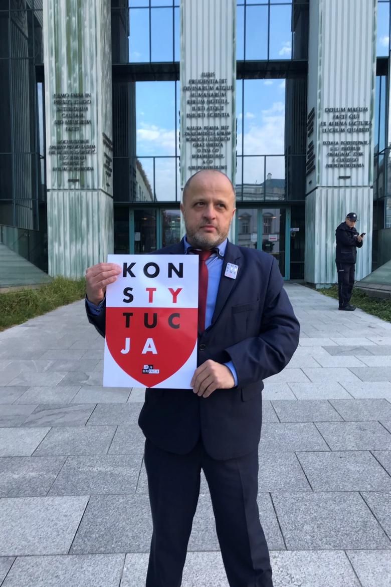 Mężczyzna z plakatem KonsTYtucJA na tle Sądu Najwyższego