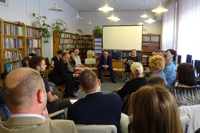 Ludzie siedzą na sali bibliotecznej