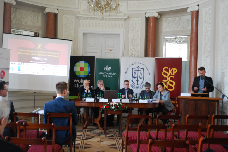 Paneliści przy stole i bannery organizatorów