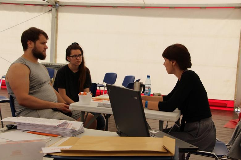 zdjęcie: w namiocie przy stoliku siedzą trzy osoby