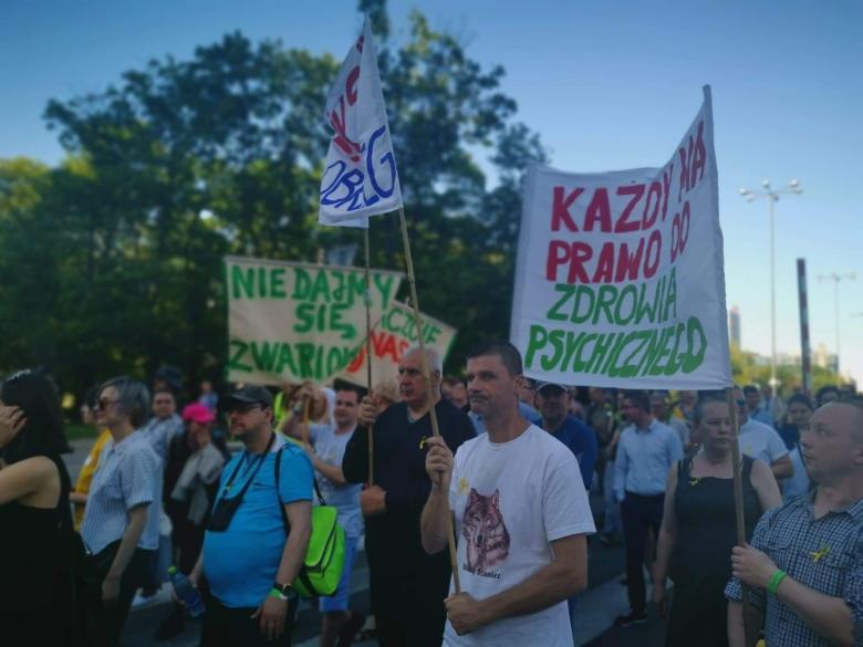 Ludzie maszerują z transparentem "Każdy ma prawo do zdrowia psychicznego"