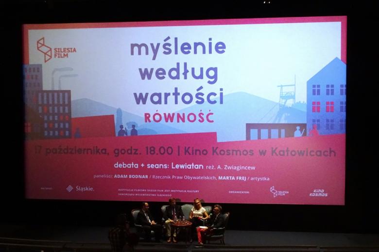 Trzej mężczyźni i kobieta rozmawiają w panelu. Za nimi ogromny napis na biało0czerwonym tle: Myślenie według wartości. Równość