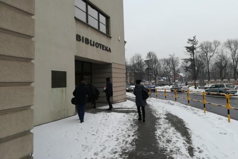 Ludzie wchodzą do budynku z napisem Biblioteka