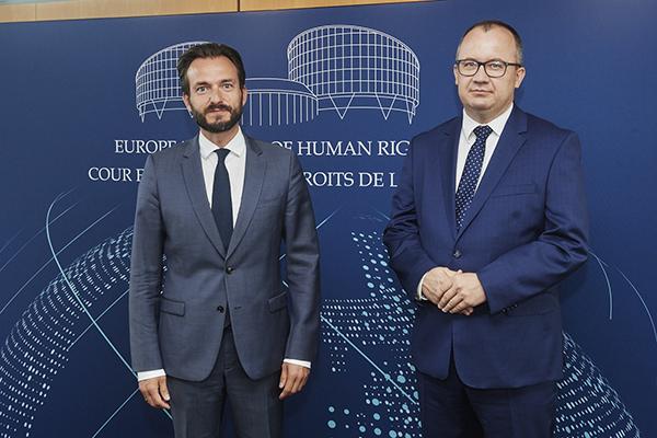 dwóch mężczyzn w garniturach pozuje na niebieskiej ściance