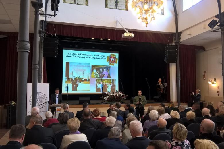 Zdjęcie: uroczysta akademia. Ludzie siedzą, mężczyzna przemawia