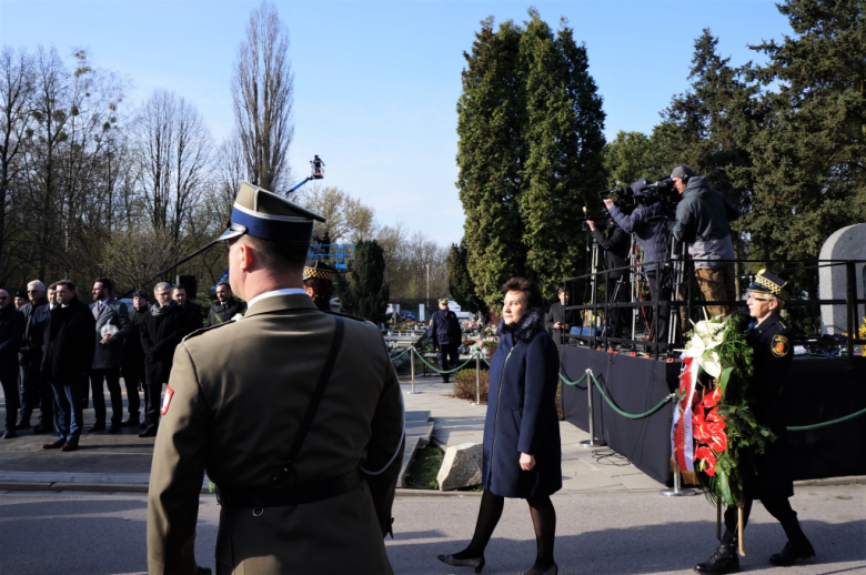 Osoba składa wieniec na cmentarzu