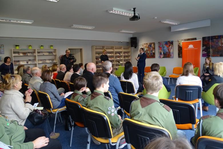 Luidzie siedzą w nowoczesnej sali na kolorowych krzesłach