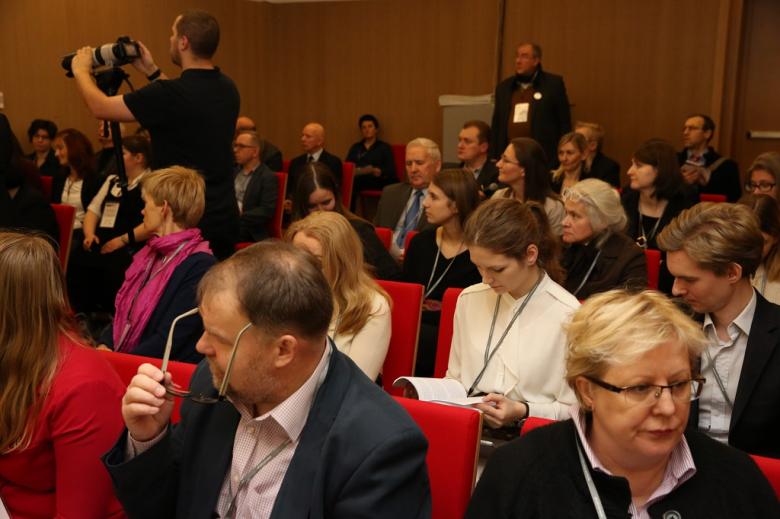 Sala konferencyjna pełna ludzi, czerwone krzesła