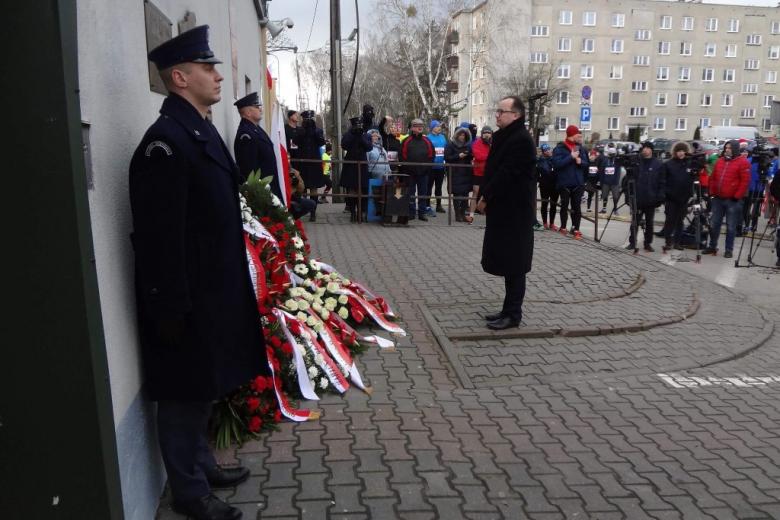 Mężczyzna stoi przed tablica pamiątkową