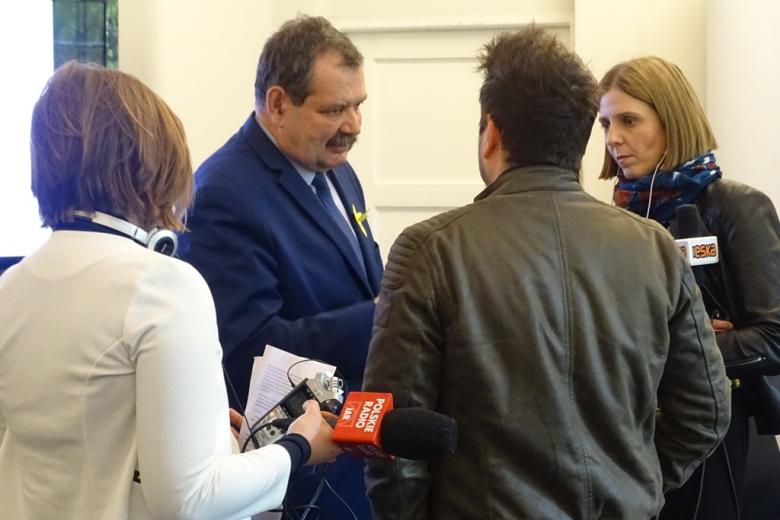 Mężczyzna wśród dziennikarzy, mikrofony radiowe