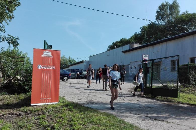 Pomarańczowe bannery przed budynkiem, ludzie w letnich strojach