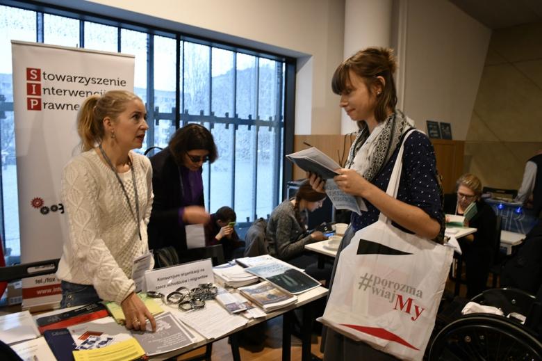 Ludzie przy stołach z publikacjami