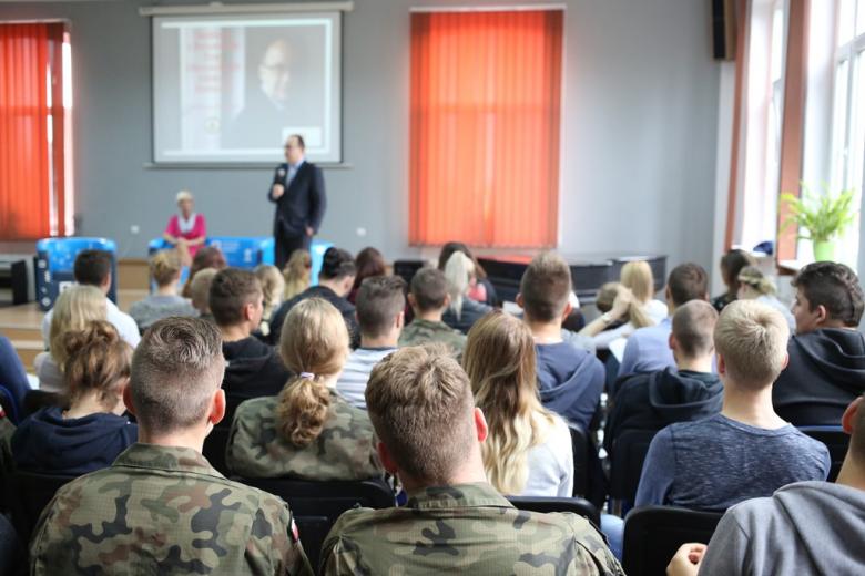 Mężcztzna w auli szkoły ponadpodstawowej, uczniowie