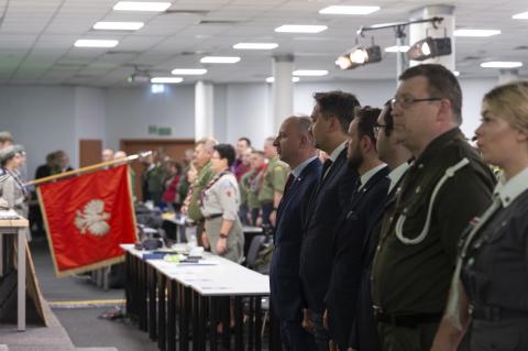 RPO Marcin Wiącek stojący razem z innymi gośćmi Zjazdu ZHP na baczność i spoglądający w stronę pocztu sztandarowego harcerzy