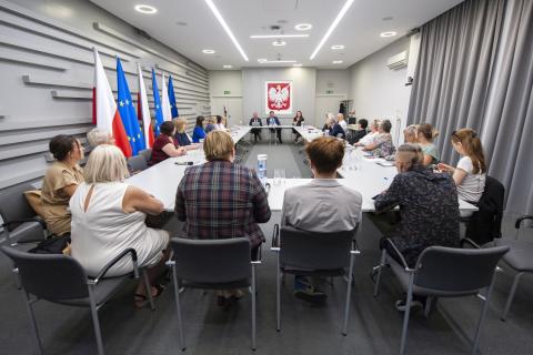 Grupa kilkunastu osób siedząca przy stole konferencyjnym