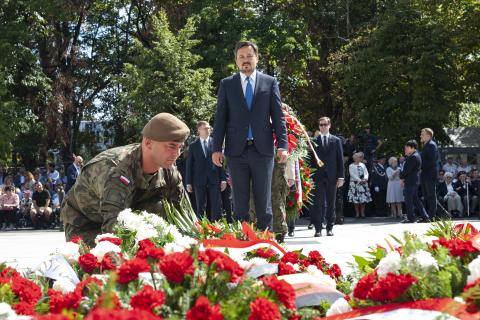 Rzecznik, przed nim żołnierz kuca i składa wieniec