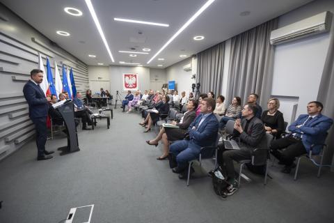 Grupa kilkudziesięciu osób siedzących w sali słucha wystąpienia RPO Marcina Wiącka w trakcie konferencji