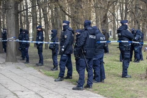 Grupa policjantów stojących w parku między drzewami