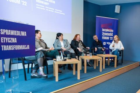 Sześć osób siedzących na podwyższeniu przy stołach, w tle rollup z napisem "Forum Bezpiecznej Żywności"