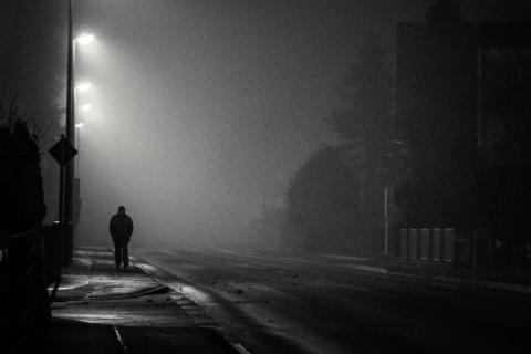 osoba idąca pustą ulicą w nocy przy słabym oświetleniu 